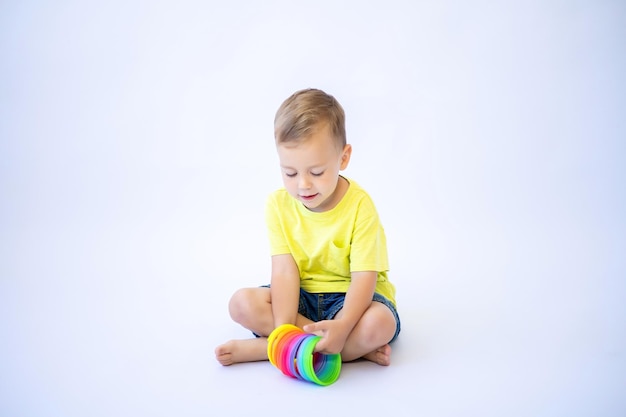 Heureux tout-petit garçon jouant avec des jouets en plastique brillants sur un fond blanc isolé des jouets éducatifs pour les enfants