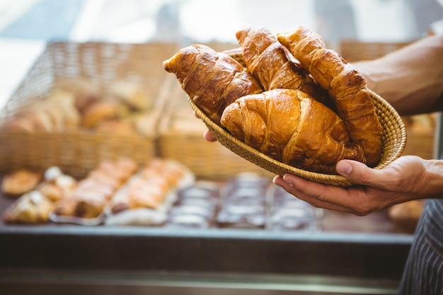 heureux travailleur tenant un panier de croissants