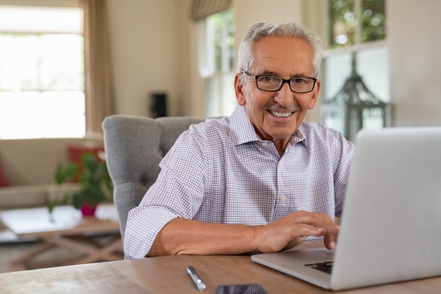 Heureux vieillard souriant avec ordinateur portable