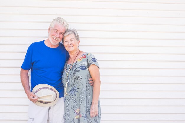 Heureux vieux couple souriant avec chapeau à la main dans une journée ensoleillée