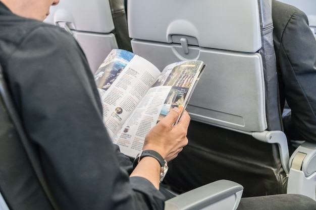 Heureux voyageur lisant un magazine dans un avion