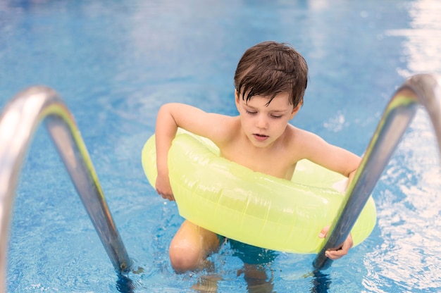 High angle boy in pool with float