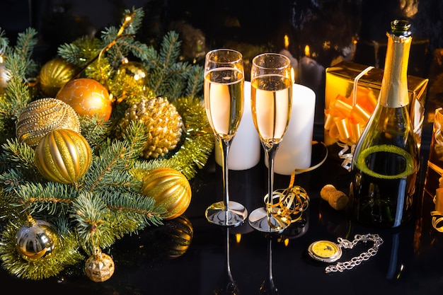 High Angle Festive Still Life - Deux verres de champagne mousseux avec bouteille, bougies, cadeaux, montre de poche et décorations de Noël sur fond noir
