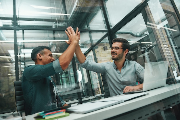 Photo highfive deux jeunes et beaux hommes en tenue décontractée collègues se donnant highfive et