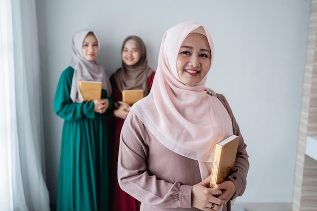 Hijab femmes souriantes tiennent le livre sacré d'Al-coran