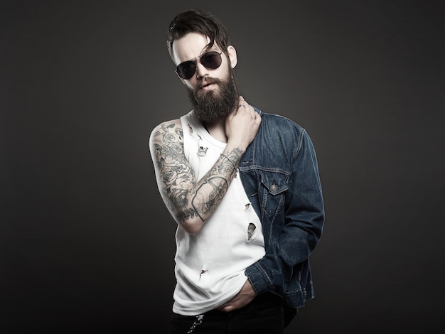 Hipster barbu élégant garçon en jeans et lunettes