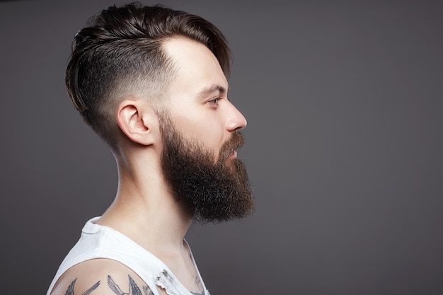 Hipster barbu garçon avec coupe de cheveux et tatouage élégants