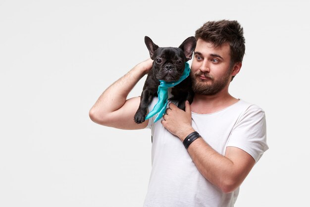 Hipster Bearded guy tenant et serrant un joli chien bouledogue français dans ses bras avec amour et jouer avec lui