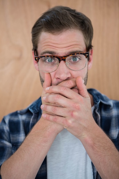 Hipster beau surpris avec les mains sur la bouche