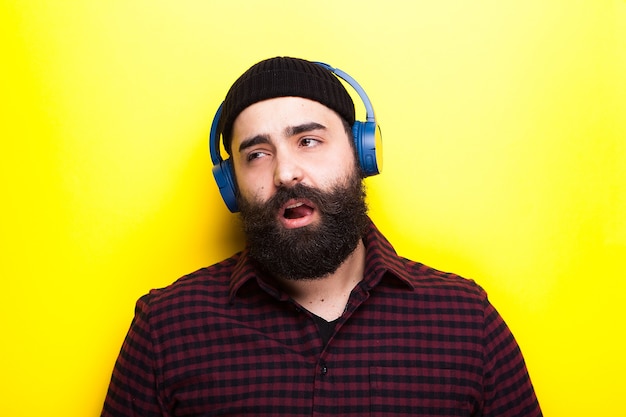 Hipster avec un casque sans fil bleu écoutant de la musique sur fond jaune