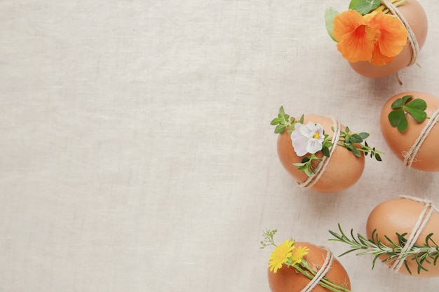 Hipster eco oeufs de Pâques avec des fleurs et des herbes sur fond d&#39;espace de copie de lin