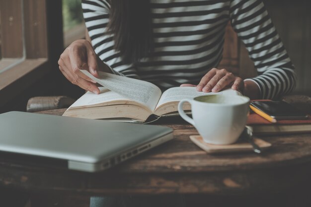 Hipster femme adolescent assis aime lire livre au café