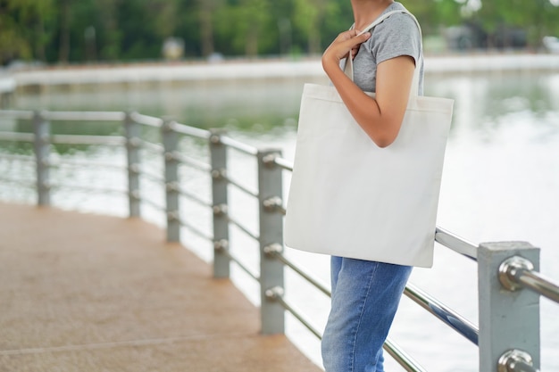 Photo hipster femme tenant un sac fourre-tout blanc