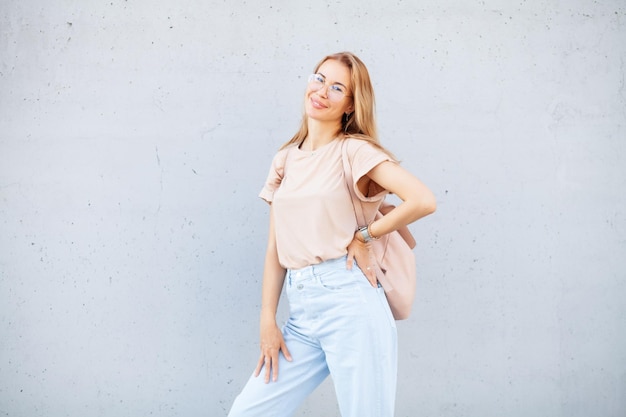 Hipster fille portant un t-shirt beige vierge et un jean posant contre un mur de rue rugueux