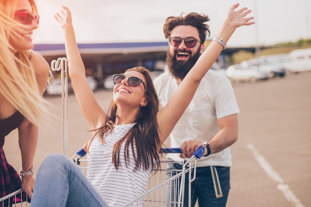 Hipster gai poussant le caddie avec des amis