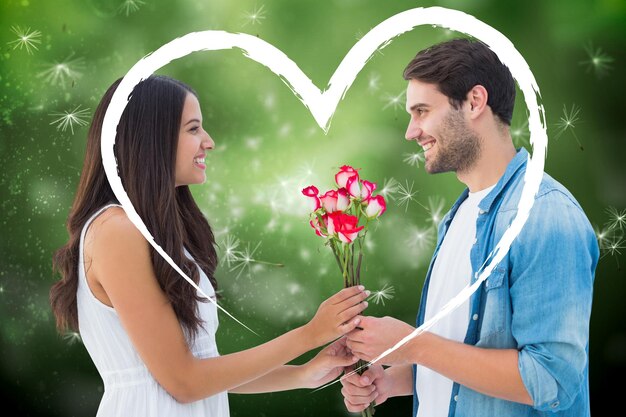 Photo hipster heureux donnant à sa petite amie des roses contre des graines de pissenlit générées numériquement sur fond vert