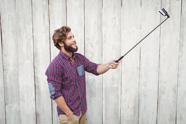 Hipster heureux en utilisant le bâton de selfie