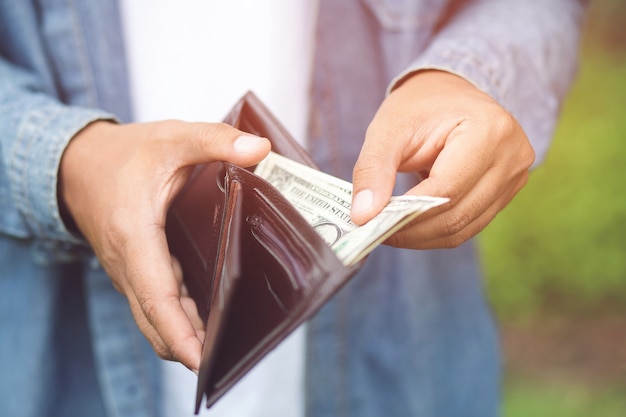 Hipster homme mains tenant portefeuille avec cartes de crédit et pile d'argent.