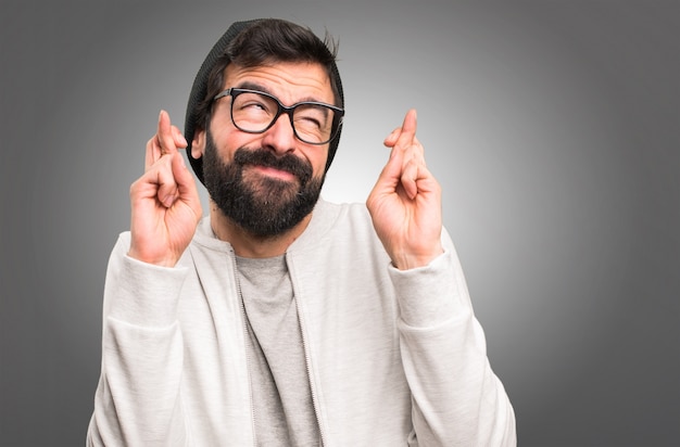 Hipster homme avec ses doigts croisés sur fond gris