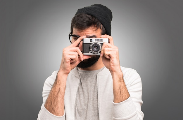 Hipster homme tenant une caméra sur fond gris