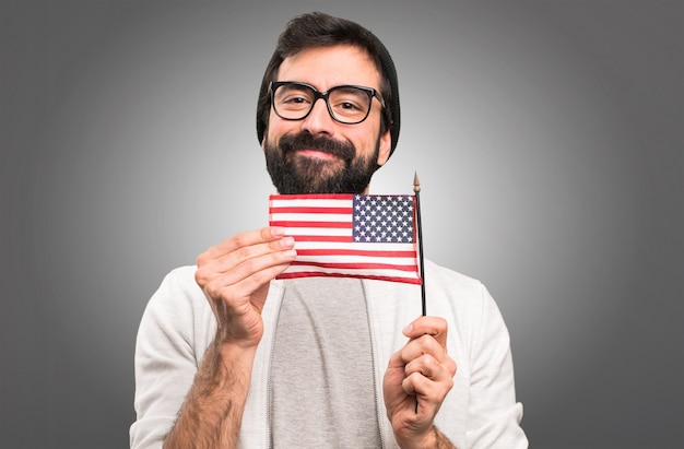 Hipster homme tenant un drapeau américain sur fond gris