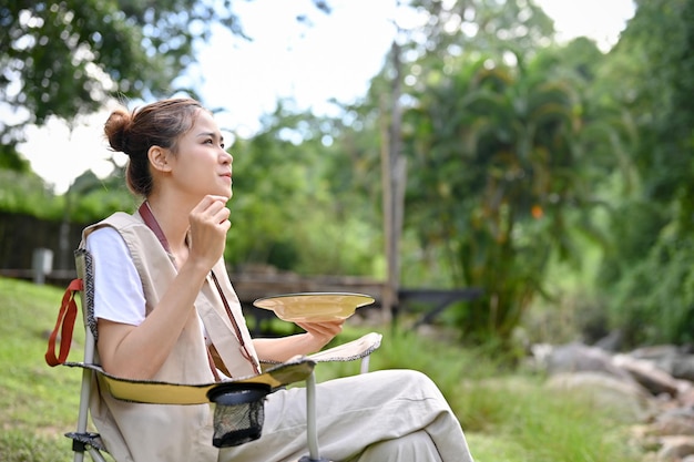 Hipster jeune campeuse asiatique aime manger son déjeuner avec la belle vue sur la nature Camping