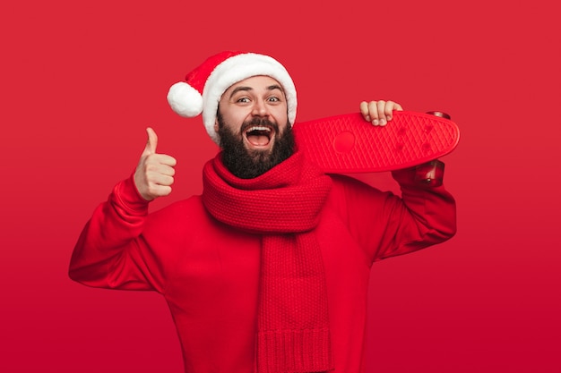 Hipster joyeux avec skateboard approuvant la fête de Noël