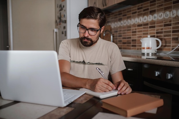 Un hipster millénaire concentré portant des lunettes écoutant de la musique préférée tout en planifiant sa journée de travail