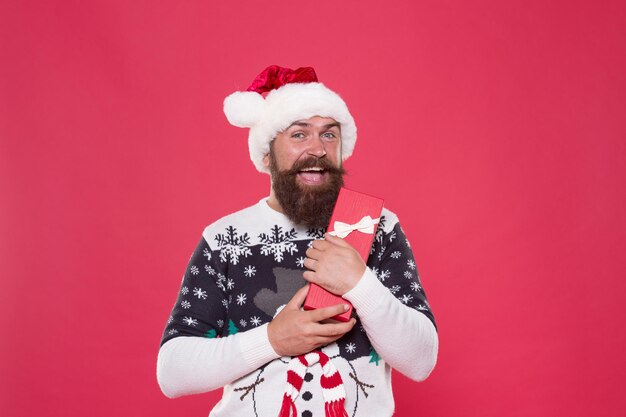 Hipster en pull d'hiver. Satisfaction des achats. Respectez les traditions. Joyeux Noël. Remise saisonnière. Cadeau du père Noël. Bonne année. Concept de cadeau de Noël. L'homme célèbre les vacances avec une boîte-cadeau.