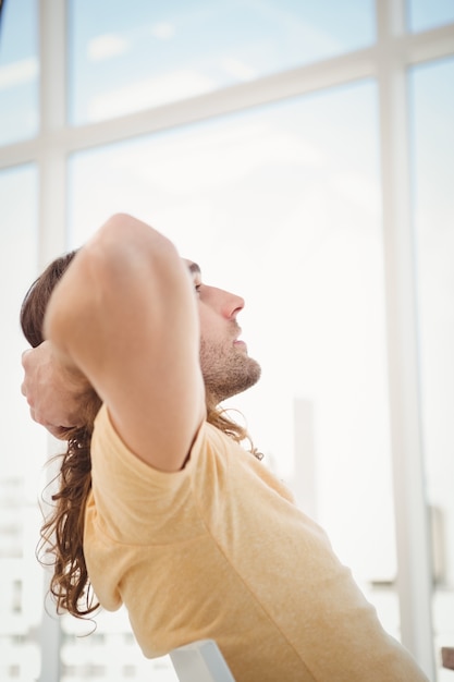 Photo hipster relaxant contre la fenêtre au bureau