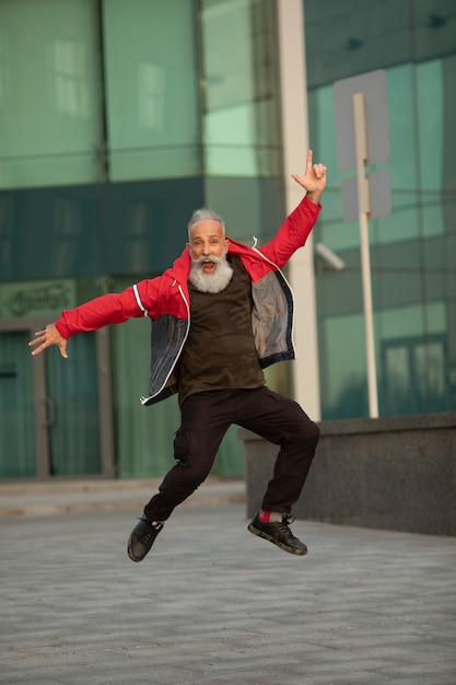 Hipster senior avec des portraits de barbe élégants. Homme mûr sautant sur la rue.