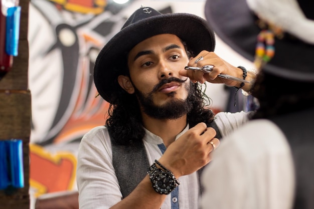 Hipster toilettant sa moustache devant le miroir Homme portant un chapeau et une montre élégante