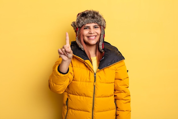 Hispanic woman smiling and looking friendly montrant le concept d'hiver numéro un