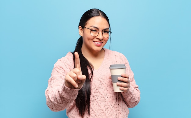 Hispanic woman smiling fièrement et en toute confiance faisant le numéro un pose triomphalement, se sentant comme un leader