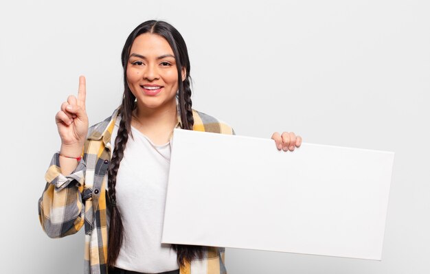 Hispanic woman smiling et à la sympathique, montrant le numéro un ou d'abord avec la main en avant, compte à rebours