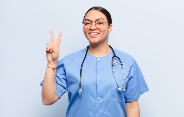 Hispanic woman smiling et à la sympathique, montrant le numéro deux ou seconde avec la main en avant, compte à rebours