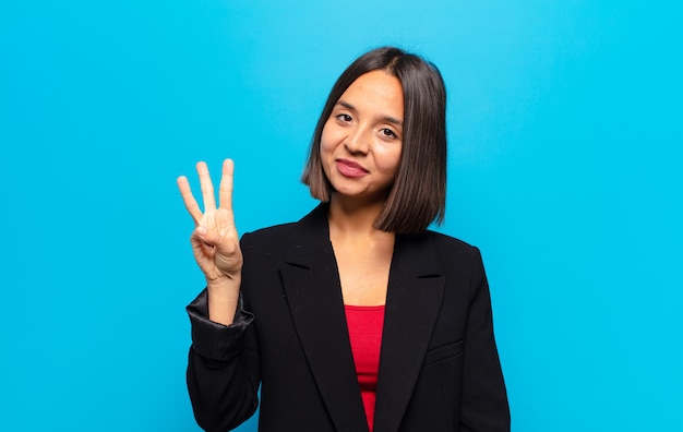 Hispanic woman smiling et à la sympathique, montrant le numéro trois ou troisième avec la main en avant, compte à rebours