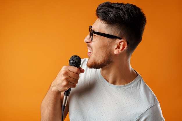 Hispanique jeune bel homme chantant avec joie dans le microphone