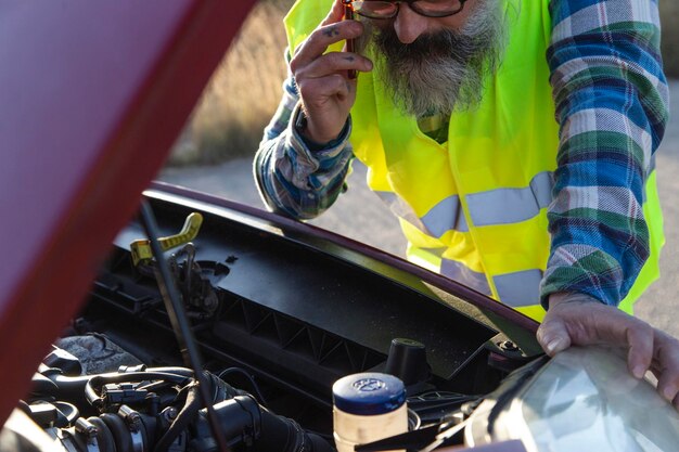 Hispanique parlant au téléphone pour demander à un mécanicien de venir réparer sa voiture en panne sur la route