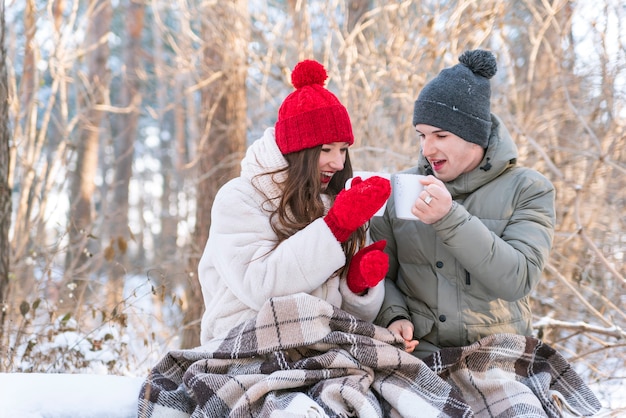 Histoire d'amour. Jeune couple dans le parc d'hiver est enveloppé dans une couverture et boire du thé.