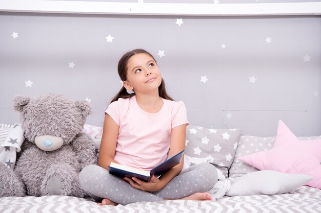 Une histoire qui fait rêver. Petite fille lire et imaginer. Rêveur mignon avec livre et jouet. Imagination et fantaisie des enfants. La lecture nourrit l'imagination. Inspirer l'imagination des enfants.