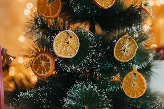 En Hiver, L'arbre Est Décoré D'oranges Séchées à L'extérieur, De Branches Vertes Sur Fond Flou Et De Bokeh Jaune-or. Décor Festif Dans Un Style éco. Joyeux Noël.