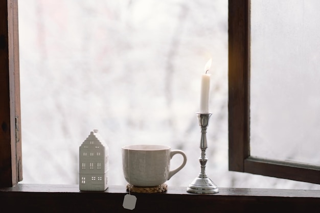 L'hiver confortable still life Tasse de thé chaud avec une bougie et décoration sur un rebord de fenêtre en bois vintage Cosy home concept Sweet home