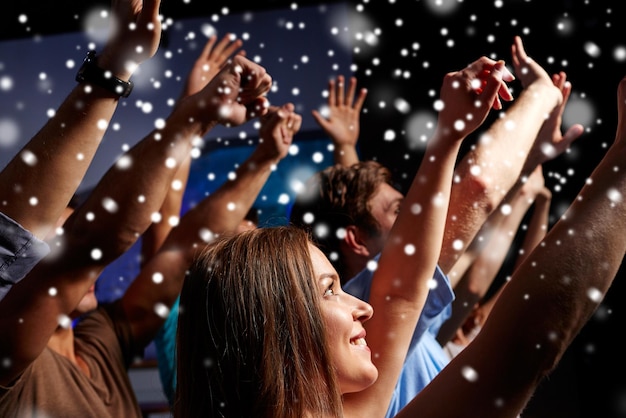 Photo hiver, fête, vacances, vie nocturne et concept de personnes - amis souriants agitant la main au concert en club et effet de neige