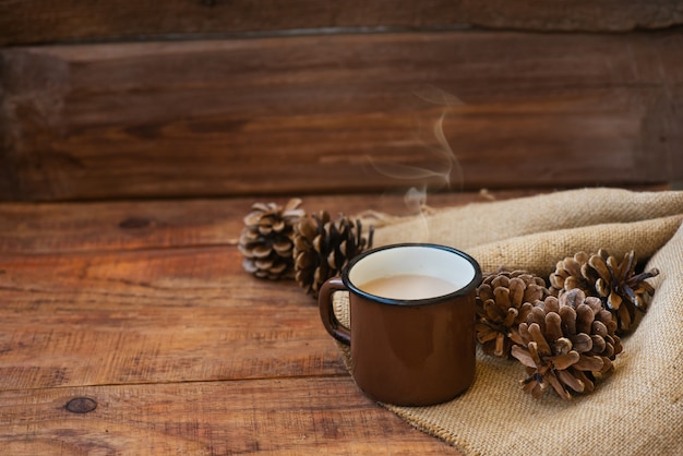 Hiver, fond de Noël dans un style rustique. Une tasse vintage en métal avec du thé au lait chaud se dresse sur une nappe