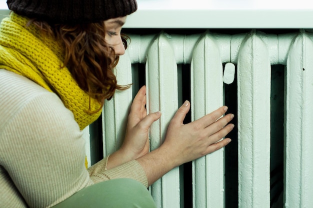 hiver froid dans l'appartement une fille se réchauffe les mains près de la saison de chauffage de la batterie