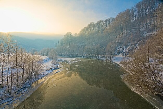 En hiver, le lit de la rivière non gelé dans le fond d'hiver des banques enneigées