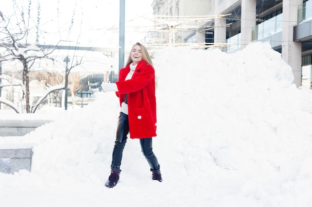 Hiver, mode, concept de personnes - mode Portrait d'une belle jeune femme se promène dans la ville souriante manteau de fourrure rouge gros plan flocons de neige hiver froid, respire l'air frais au jour de gelée d'hiver. le coucher du soleil