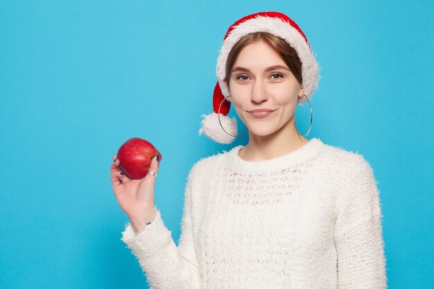 Hiver, Noël, gens, concept de beauté - jolie blonde portant un chapeau de Noël sur une surface bleu clair