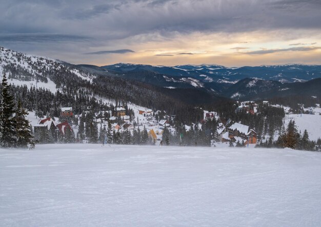 Photo hiver pittoresque venteux et nuageux matin alpes vue sur la célèbre station de ski ukrainienne de dragobrat depuis la crête de la montagne svydovets